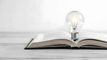 Light bulb resting on open book symbolizing ideas and knowledge discovery photo