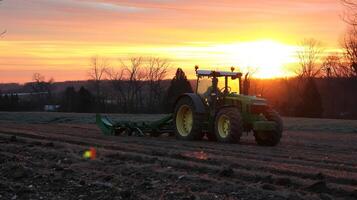 Sunrise over farmland with tractor plowing fields photo