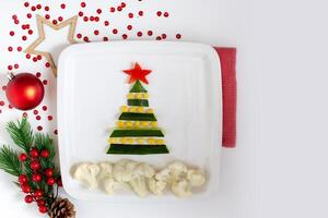 New Year's table decor, cucumber and corn salad in the form of a New Year tree, on a white plate photo