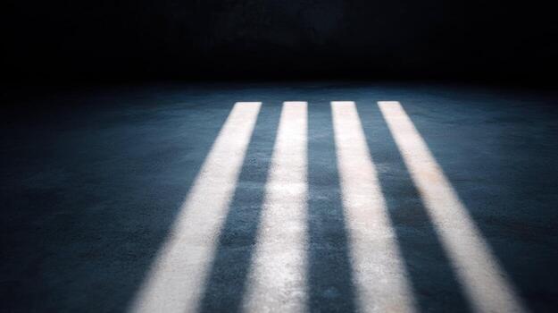 Sunlight casting bars on concrete floor with strong shadows creating dramatic mood in a dark interior space. photo
