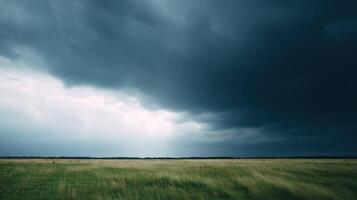 Storm clouds gathering over vast green grass field creating a dramatic and moody natural landscape with contrasting dark sky and peaceful open countryside scenery. photo