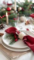 Elegant holiday table setting with red napkins and evergreen decor photo