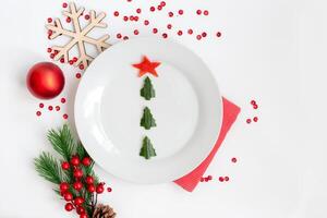 A white plate with a cucumber snack in the form of a Christmas tree photo