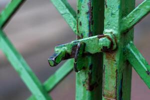 Close-up of weathered green metal gate with rusty latch and textured surface photo