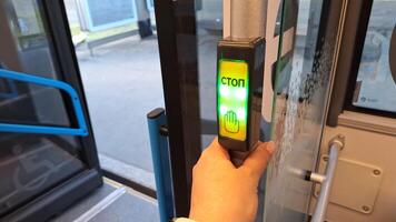 Moscow, Russia - April 26, 2025.Hand pressing stop button with cyrillic text on public bus exit photo
