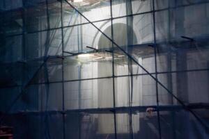 Building under renovation with scaffolding and green netting at night photo