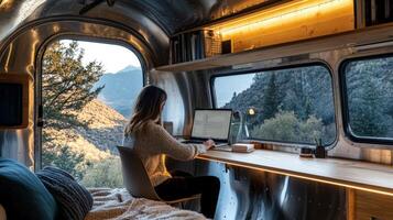 Female caucasian adult working remotely in modern camper with scenic mountain view photo