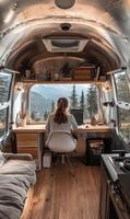 Female adult working on laptop in camper van office with mountain view photo