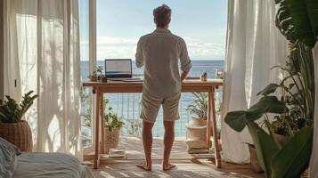 Caucasian male adult working on laptop from beachfront home office with ocean view photo