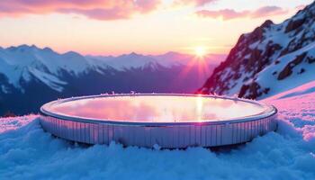 A circular pool filled with water on a snowy mountain top, sunset with pink and orange sky, snow-covered mountains in the background photo