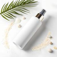A white bottle with a spray cap surrounded by a circle of sand and small rocks, a palm leaf in the background on a white surface photo