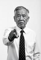 Filipino oldman with receding gray hair, wearing a buttoned-down white shirt and a polka dot tie, pointing directly forward with a serious demeanor photo