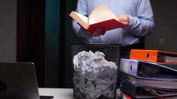 Man flipping through red book and throwing it in trash can, bin video