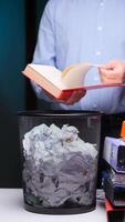 vertical Man flipping through red book and throwing it in trash can, bin video