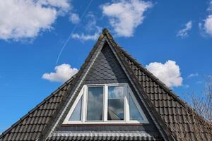 Triangular dormer window is illuminating the attic of a modern house photo