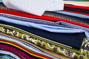 Stack of colorful fabrics showing various patterns and textures photo