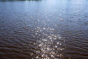 Sunlight reflecting on slightly rippled water surface photo