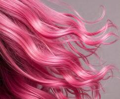 Close-up of wavy, shiny pink hair against a neutral gray background photo