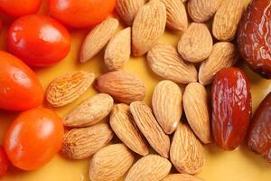 Colorful assortment of nuts and dates on a yellow background photo