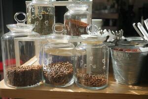 Coffee beans and spices stored in glass containers at a market photo