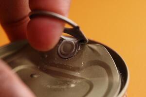 Opening a can with a finger on a bright yellow background photo