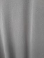 A close-up image of a smooth grey fabric with subtle vertical folds, giving it a soft and elegant appearance. photo