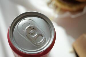 Soda can with open tab beside delicious burger meal at lunchtime photo