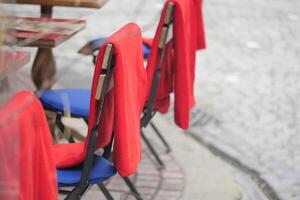 Empty chairs with red covers on a cobblestone street in autumn photo