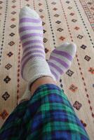 Cozy feet in colorful socks on a patterned carpet at home photo