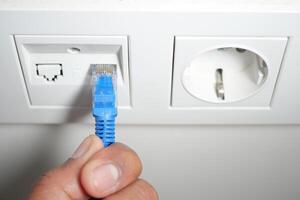 Connecting an ethernet cable to a wall socket in a modern setting photo