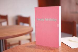 Happy birthday card on a table in a cozy cafe setting photo