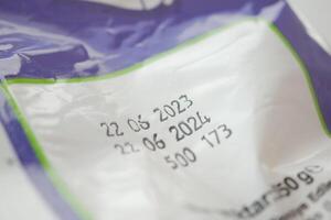 Package with expiration dates and product details in close-up view photo