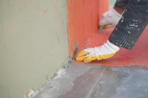 Worker applying mesh for wall reinforcement at construction site photo