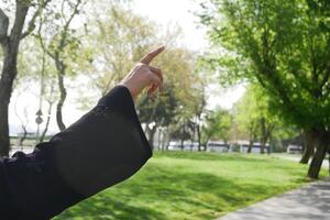 Person gestures towards the trees in a bright park setting photo