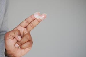 Applying skincare cream on fingers with a neutral background photo