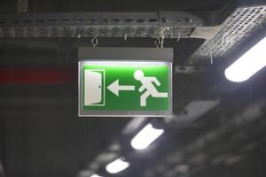 Emergency exit sign illuminated in a dimly lit building corridor photo