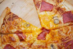 Slices of pizza topped with ham and cheese on a wooden board photo