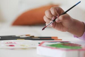 Child creating art with paintbrush in a cozy indoor setting photo