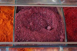 Colorful spices arranged in clear containers at a market stall photo
