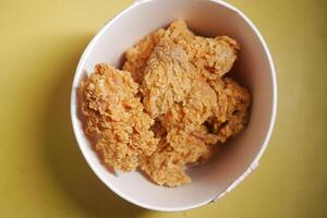 Crispy fried chicken served in a bowl on a yellow surface photo