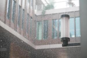 Snow falls gently outside a modern building courtyard photo
