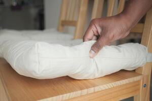 Hand adjusting a cushion on a wooden chair in a cozy setting photo