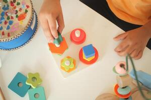 Child playing with colorful shape sorting toy on table photo