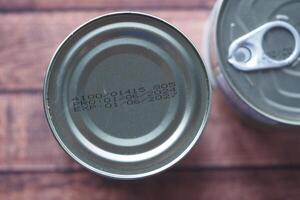 Cans with expiration dates and production codes on wooden surface photo