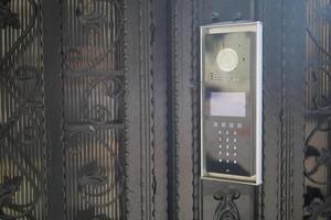 Modern intercom system mounted on an ornate black gate photo