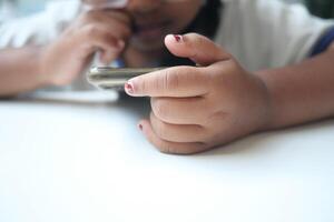 Child engaged with smartphone while resting on table photo