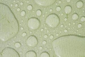 Water droplets form patterns on a smooth green surface photo