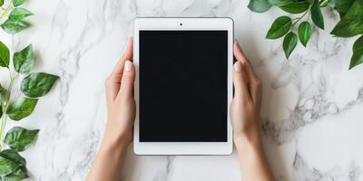 Modern technology concept with hands holding a sleek tablet on marble surface photo