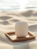 Minimalist white ceramic cup on wooden tray in sunlit sandy environment for design and promotion photo