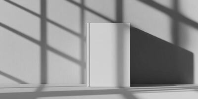 Minimalist white hardcover book on light grey background with shadow patterns photo